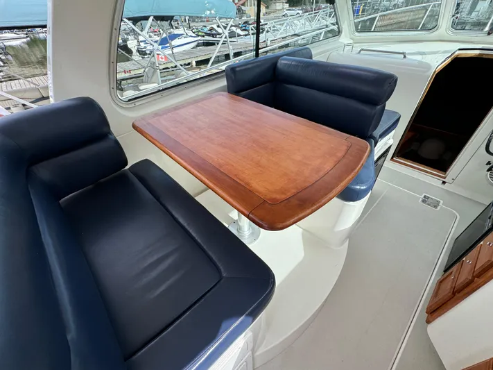 "flying Low" Yacht Photos Pics 2008 Back Cove 33 interior with blue seating and wooden table, docked at marina.