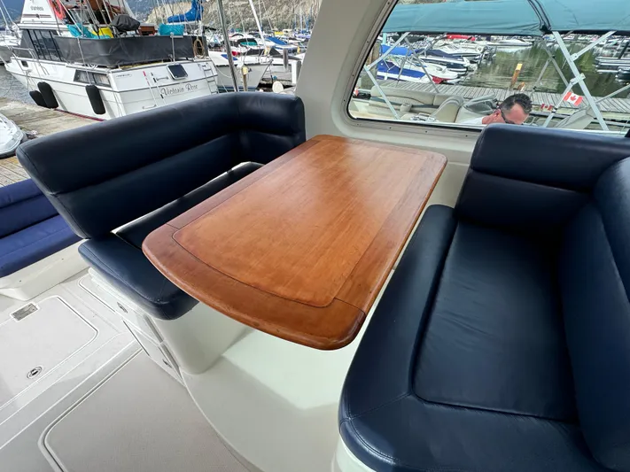 "flying Low" Yacht Photos Pics Interior of 2008 Back Cove 33 boat with wooden table and blue seating.