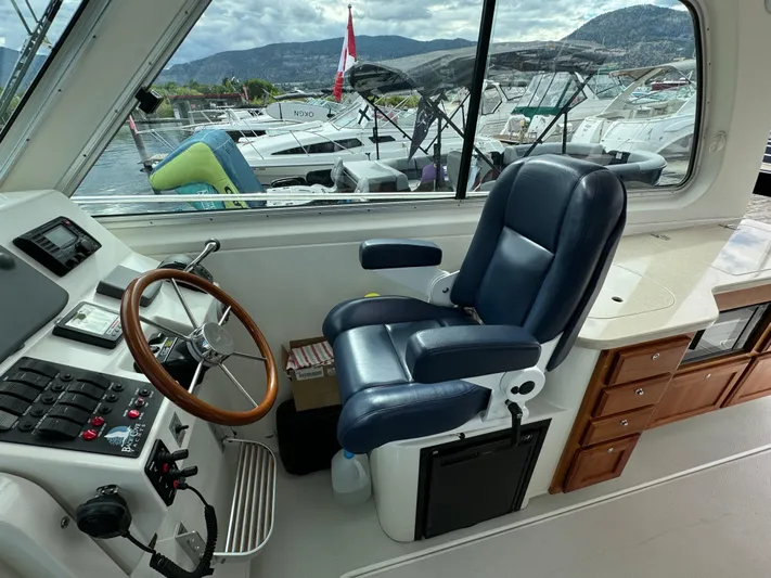 "flying Low" Yacht Photos Pics 2008 Back Cove 33 boat helm with leather seat, wooden steering wheel, and marina view.