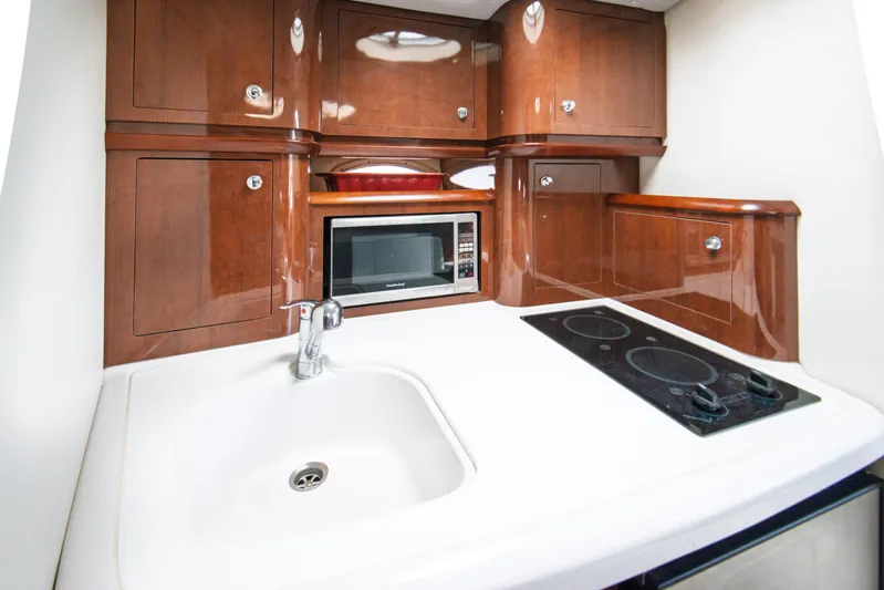  Yacht Photos Pics 2014 Four Winns V375 yacht kitchen with wooden cabinets, sink, microwave, and stovetop.