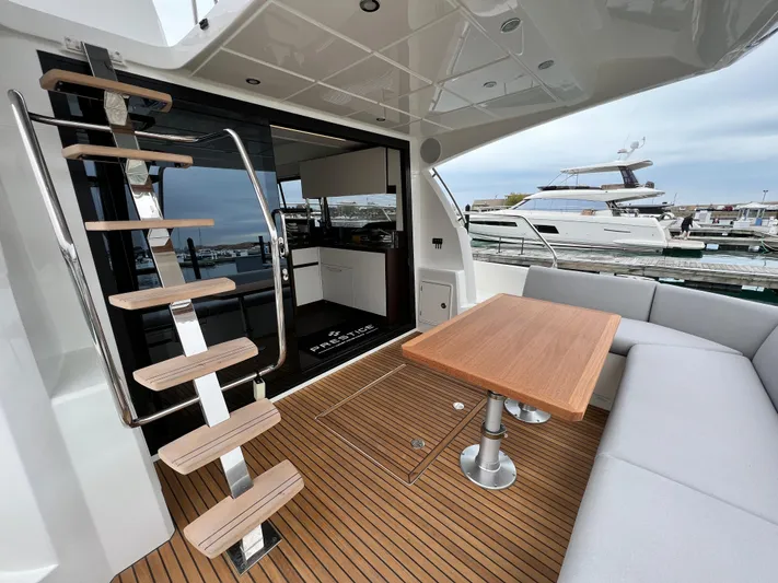  Yacht Photos Pics Prestige 460 Flybridge 2023 yacht interior with wooden table, stairs, and seating area.
