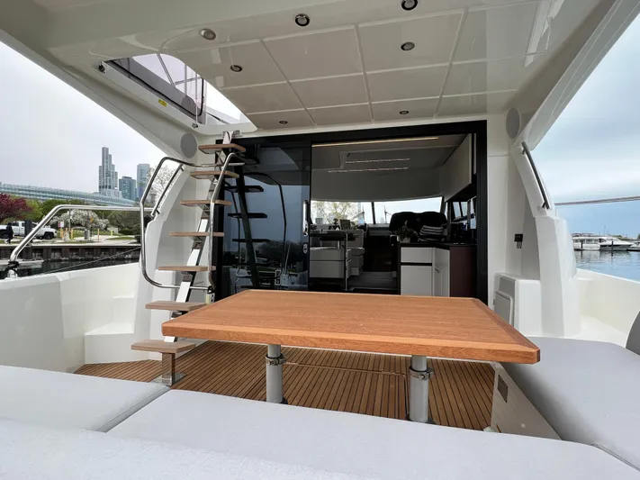  Yacht Photos Pics 2023 Prestige 460 Flybridge yacht interior with wooden table and staircase, docked at marina.