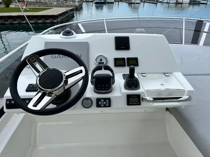  Yacht Photos Pics 2023 Prestige 460 Flybridge helm with steering wheel and control panel by the water.