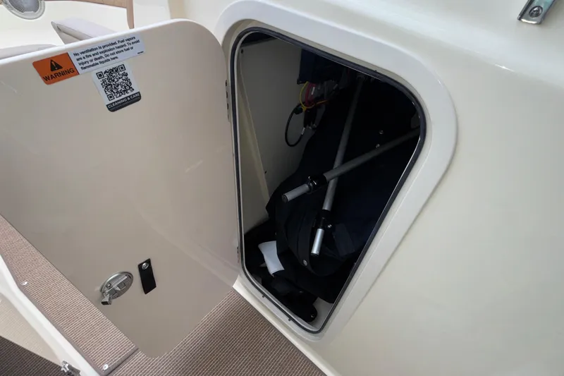  Yacht Photos Pics Storage compartment on 2026 Chris-Craft Calypso 28 boat, featuring safety warning and QR code.