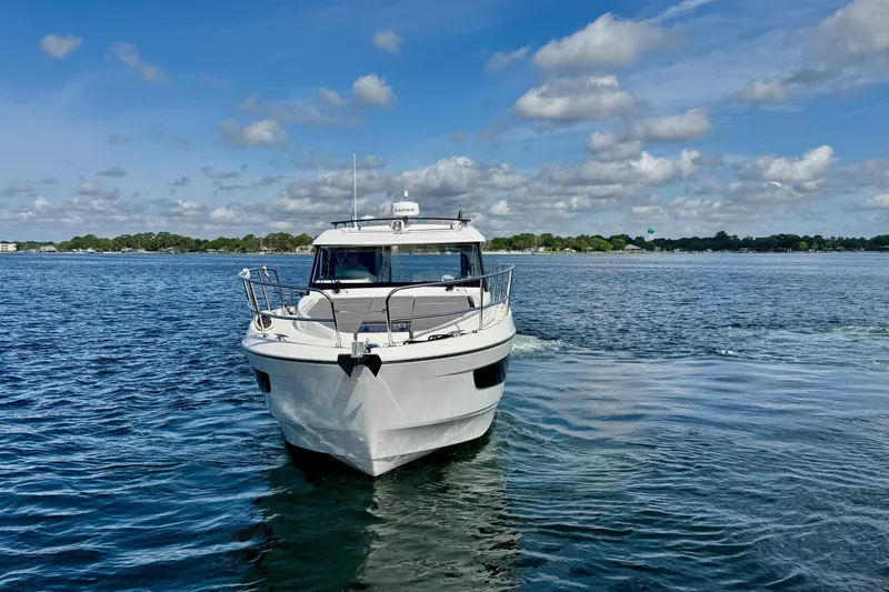 Venture Yacht Photos Pics 2024 Beneteau Antares 11 cruising on a serene lake under a blue sky.