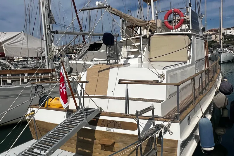 Apta Yacht Photos Pics 1989 Grand Banks 36 Classic yacht docked in marina, featuring wooden railings and a red flag.