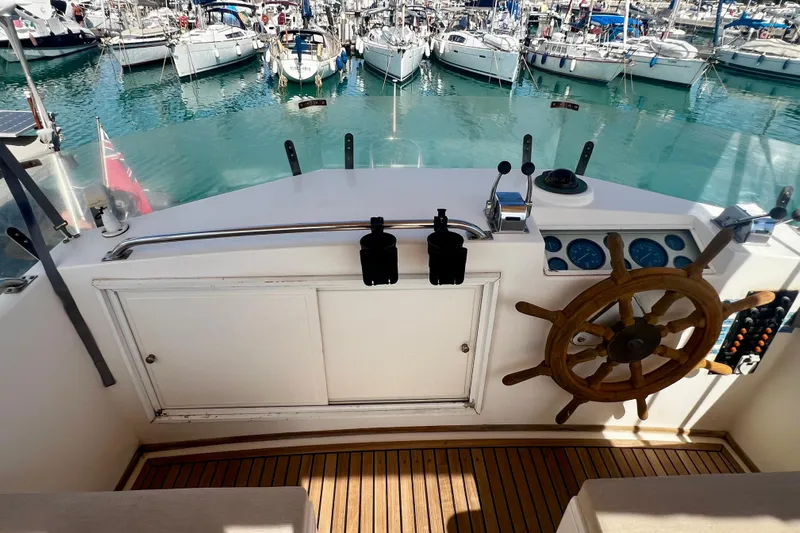 Apta Yacht Photos Pics Helm of 1989 Grand Banks 36 Classic yacht with wooden wheel, overlooking marina.