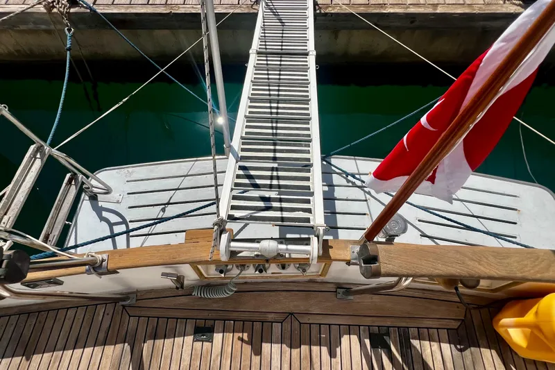 Apta Yacht Photos Pics 1989 Grand Banks 36 Classic yacht with wooden deck and gangway, docked with a flag.