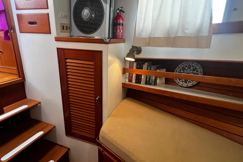 Apta Yacht Photos Pics Cozy interior of 1989 Grand Banks 36 Classic with books, fan, and wooden accents.