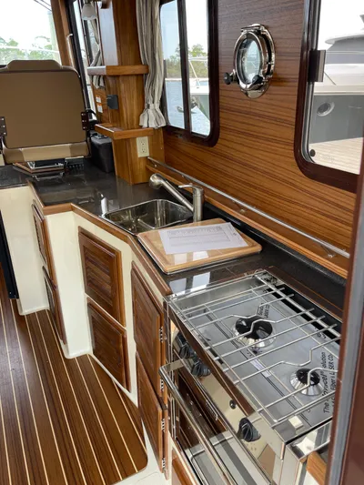  Yacht Photos Pics 2023 Ranger Tugs R-31 CB interior kitchen with stove, sink, and wood finish.