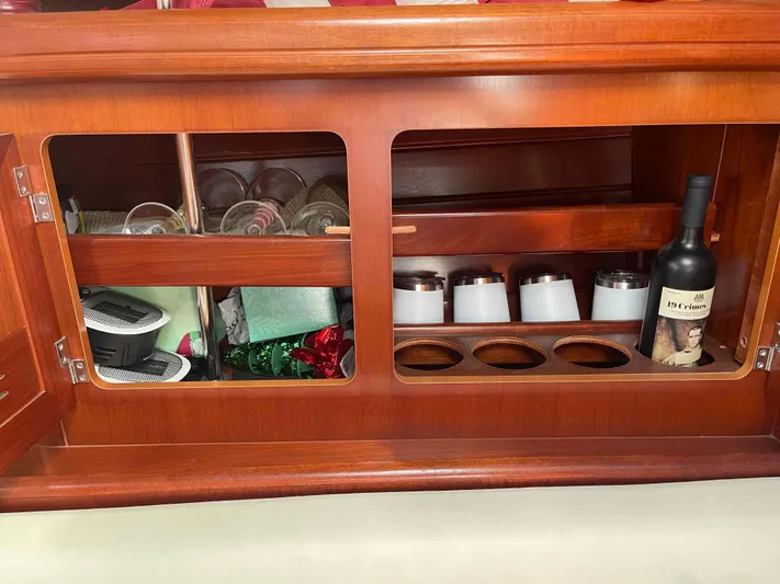 Tiramisu Yacht Photos Pics Wooden cabinet interior on a 2004 Beneteau Oceanis 473, featuring glasses and a wine bottle.