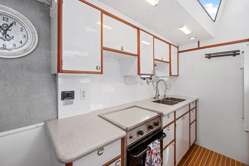 Shamrock Yacht Photos Pics Modern kitchen in 2002 Endeavour 44 Sail Catamaran with white cabinets and wood accents.