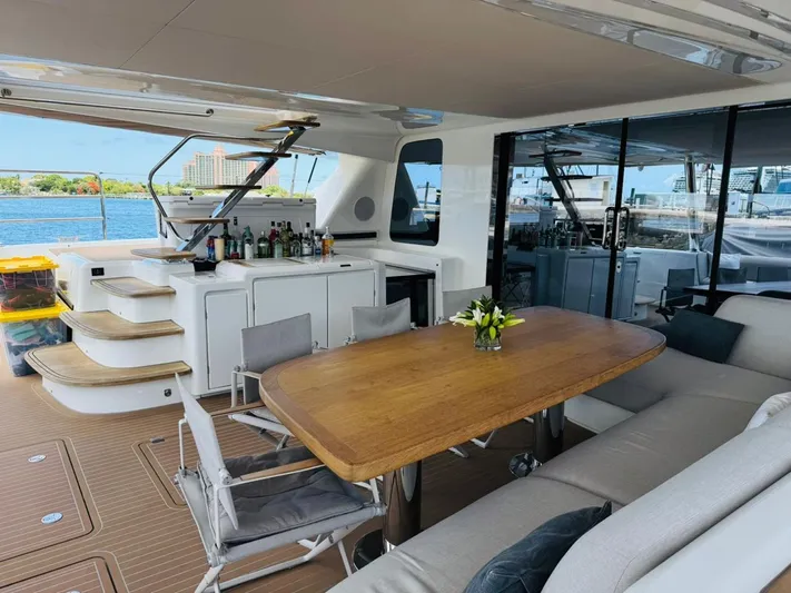  Yacht Photos Pics Luxurious 2024 Lagoon 65 yacht deck with dining area, bar, and waterfront view.