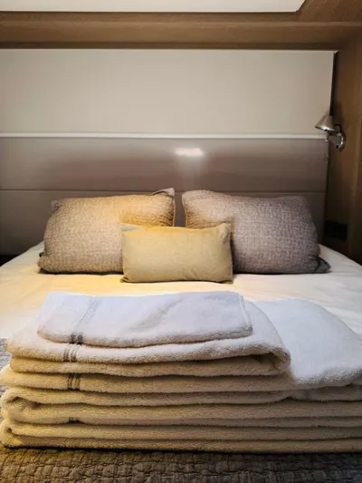  Yacht Photos Pics Luxurious bedroom in 2024 Lagoon 65 yacht with plush bedding and stacked towels.