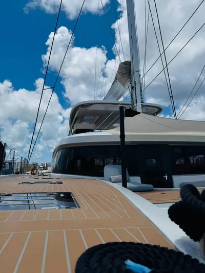  Yacht Photos Pics 2024 Lagoon 65 yacht deck with sails against a blue sky and clouds.