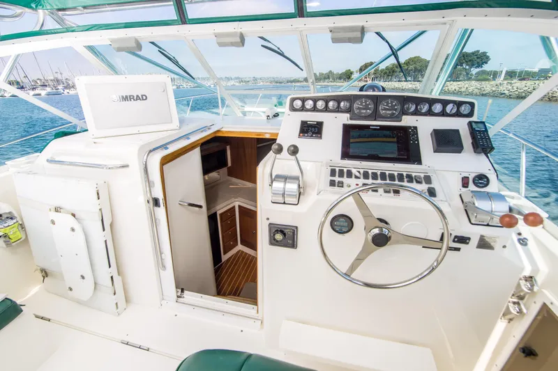 Dos Panchos Yacht Photos Pics 1997 Cabo 35 Express boat cockpit with steering wheel, control panel, and cabin entrance.