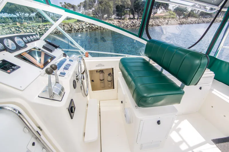 Dos Panchos Yacht Photos Pics 1997 Cabo 35 Express boat cockpit with green seating and control panel, docked by the water.