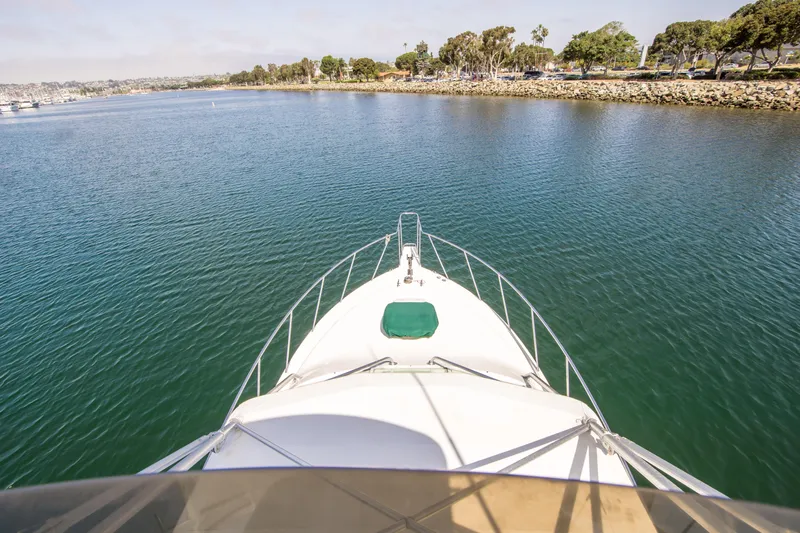 Dos Panchos Yacht Photos Pics Bow view of 1997 Cabo 35 Express yacht cruising in calm waters near shoreline.