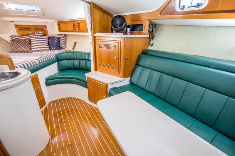 Dos Panchos Yacht Photos Pics Interior of a 1997 Cabo 35 Express boat with green seating and wood accents.