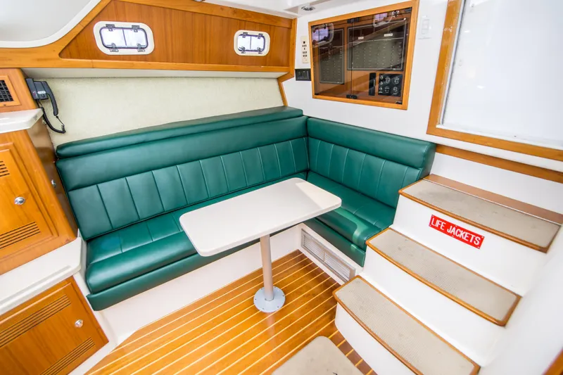 Dos Panchos Yacht Photos Pics 1997 Cabo 35 Express cabin interior with green seating, table, and life jackets.