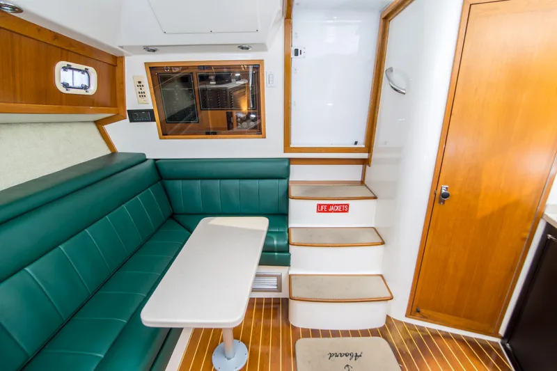Dos Panchos Yacht Photos Pics Interior of 1997 Cabo 35 Express boat with green seating and wooden accents.