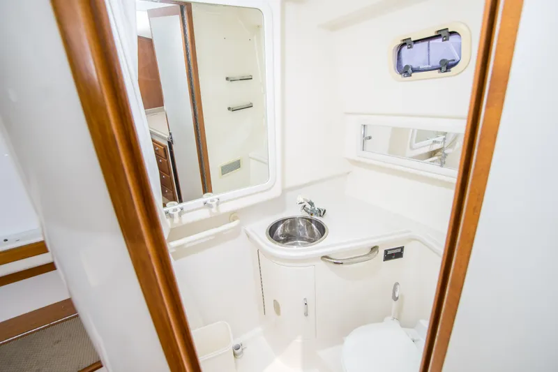Dos Panchos Yacht Photos Pics 1997 Cabo 35 Express yacht bathroom with sink, mirror, and porthole window.