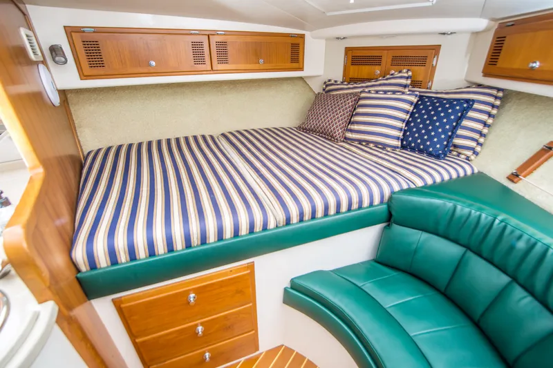 Dos Panchos Yacht Photos Pics 1997 Cabo 35 Express cabin with striped bedding, green seating, and wooden storage.