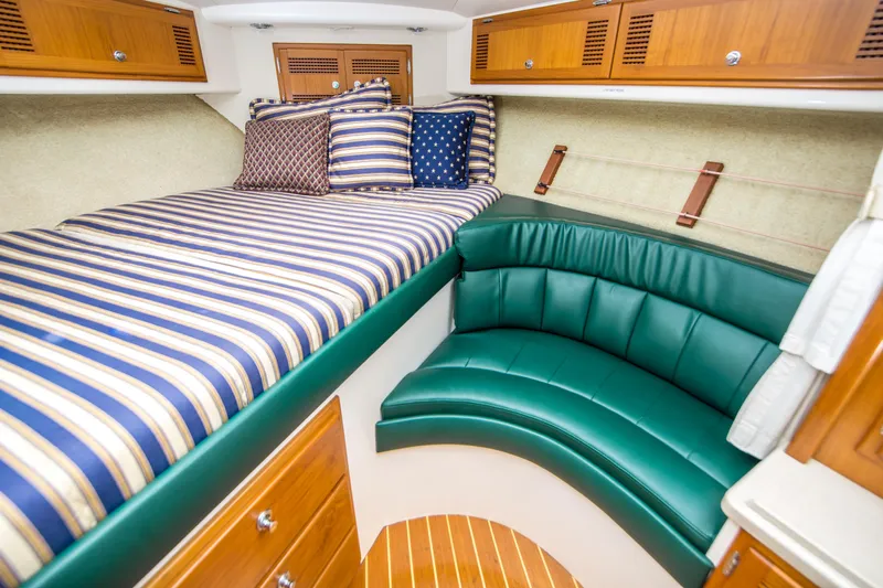 Dos Panchos Yacht Photos Pics 1997 Cabo 35 Express cabin with striped bedding and green leather seating.