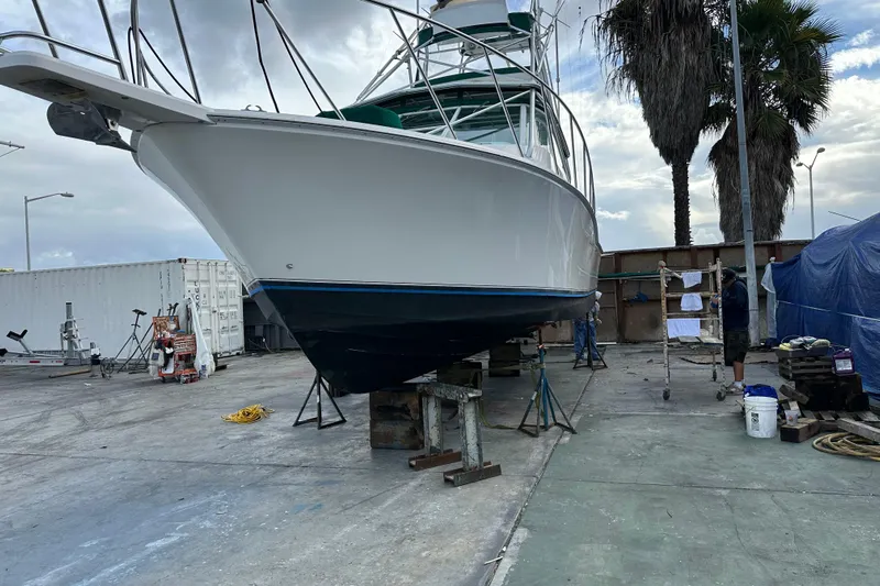 Dos Panchos Yacht Photos Pics 1997 Cabo 35 Express boat on dry dock for maintenance, surrounded by equipment and palm trees.