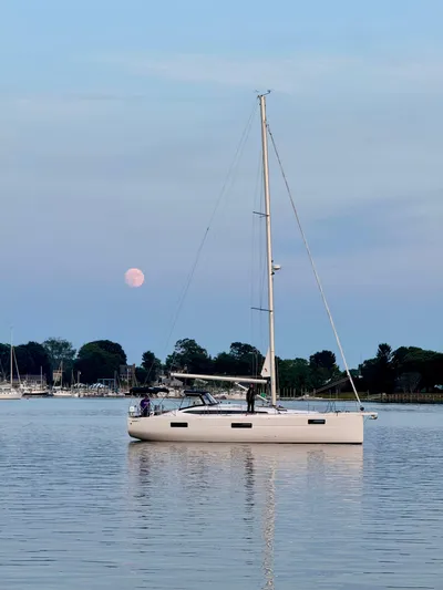 Hard Loaded Yacht Photos Pics 2024 Elan Impression 43 sailboat on calm water with a pink moon in the background.