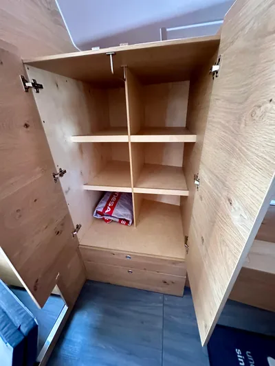 Hard Loaded Yacht Photos Pics Open wooden cabinet with shelves and drawers in Elan Impression 43, 2024 model.