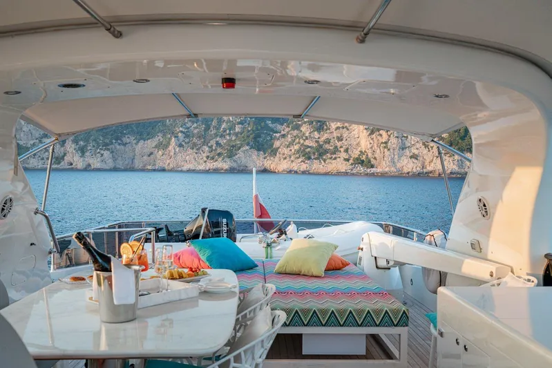 Gemini 3 Yacht Photos Pics Luxurious 2002 Maiora 24S yacht deck with colorful cushions, dining setup, and scenic ocean view.