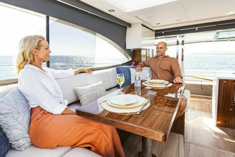  Yacht Photos Pics Couple dining on 2026 Riviera 4600 Sport Yacht Platinum Edition, enjoying ocean views.