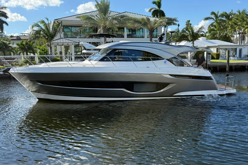 Yacht Photos Pics 2026 Riviera 4600 Sport Yacht Platinum Edition cruising on a sunny day, surrounded by palm trees.