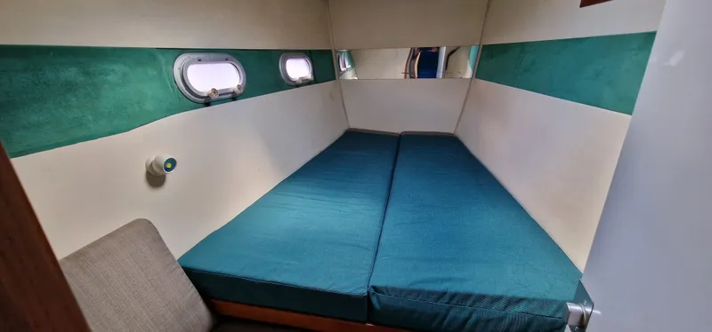 Lambada Yacht Photos Pics Cozy cabin interior of 1993 Lagoon 47 yacht with teal accents and porthole windows.