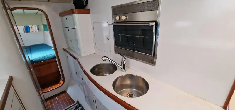 Lambada Yacht Photos Pics Compact kitchen area in a 1993 Lagoon 47 yacht with dual sinks and an oven.