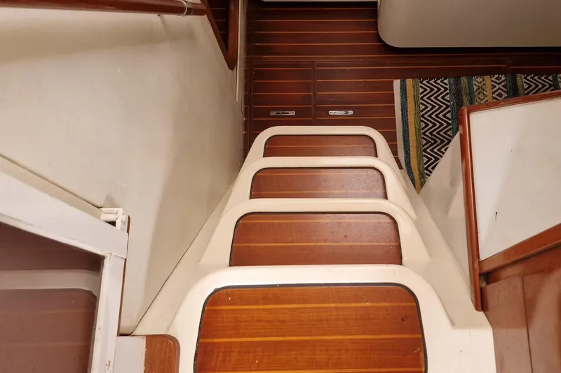 Lambada Yacht Photos Pics Wooden stairs inside a 1993 Lagoon 47 yacht, featuring a striped rug.