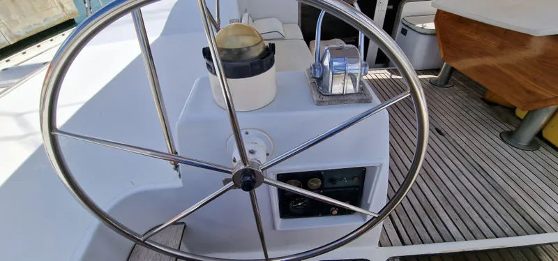 Lambada Yacht Photos Pics Steering wheel of a 1993 Lagoon 47 yacht, featuring a wooden deck and control panel.