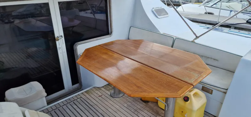 Lambada Yacht Photos Pics Wooden table on 1993 Lagoon 47 yacht deck, surrounded by seating and marine equipment.