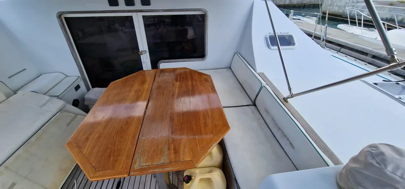 Lambada Yacht Photos Pics Spacious deck of 1993 Lagoon 47 catamaran with wooden table and cushioned seating.