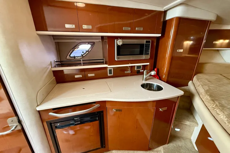 Flip Side Yacht Photos Pics 2010 Sea Ray 330 Sundancer interior kitchen with wood cabinetry, sink, microwave, and mini-fridge.