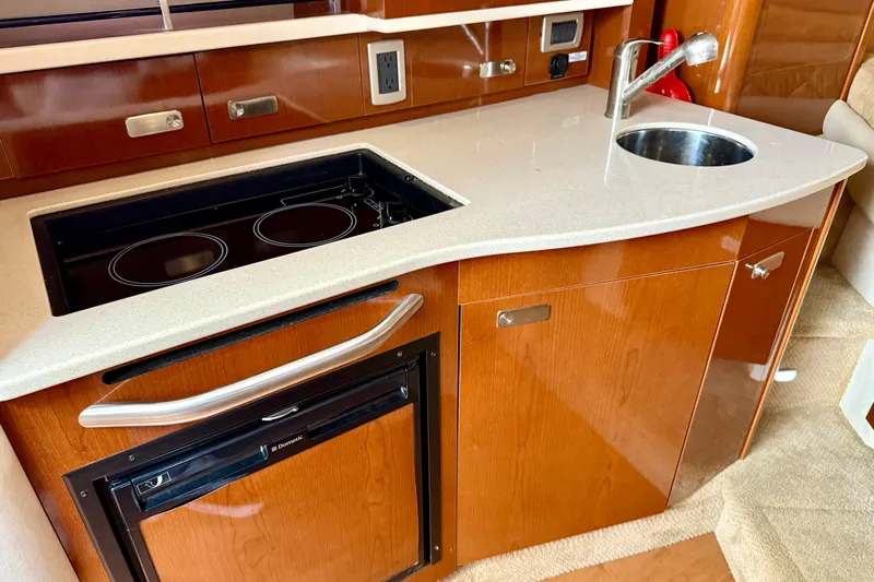 Flip Side Yacht Photos Pics 2010 Sea Ray 330 Sundancer galley with stove, sink, and wood cabinetry.