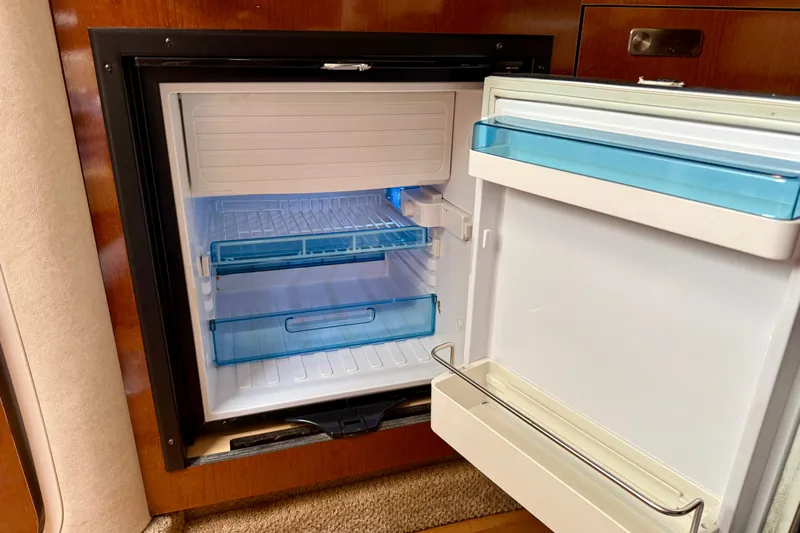 Flip Side Yacht Photos Pics Open refrigerator inside 2010 Sea Ray 330 Sundancer boat, featuring blue shelves and white interior.