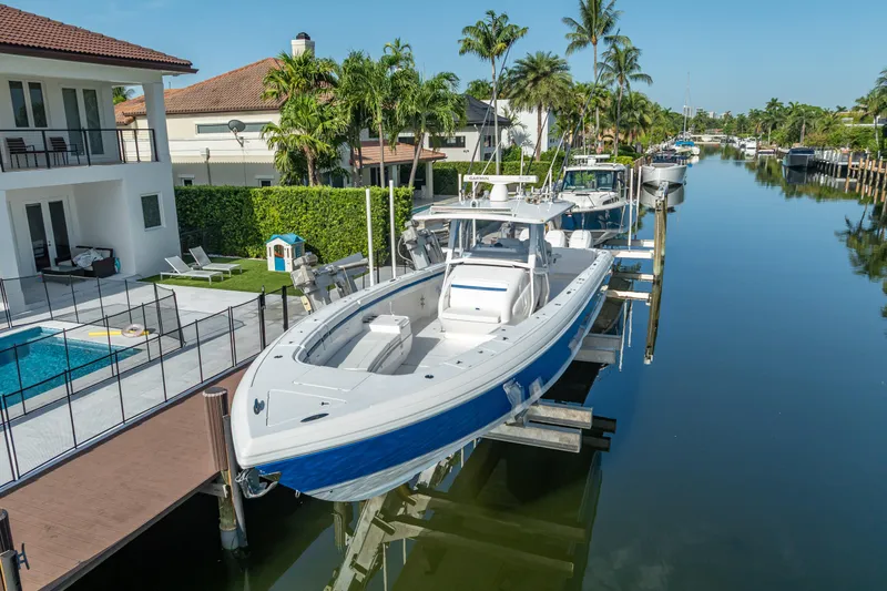 Chasing Chari Yacht Photos Pics 2016 Intrepid 400 Center Console boat docked by waterfront homes, surrounded by palm trees.