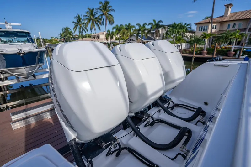 Chasing Chari Yacht Photos Pics Three powerful outboard engines on a 2016 Intrepid 400 Center Console boat, docked near palm trees.