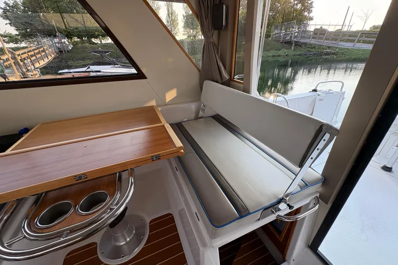 Miller Time Yacht Photos Pics 2018 Cutwater C-30 CB interior with wooden table and cushioned seating by a window.