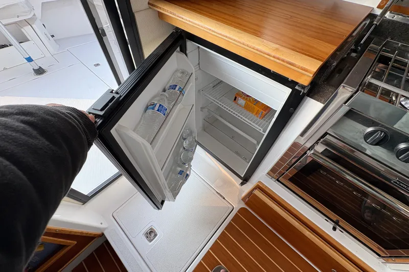 Miller Time Yacht Photos Pics 2018 Cutwater C-30 CB boat interior with open mini fridge and wooden countertop.