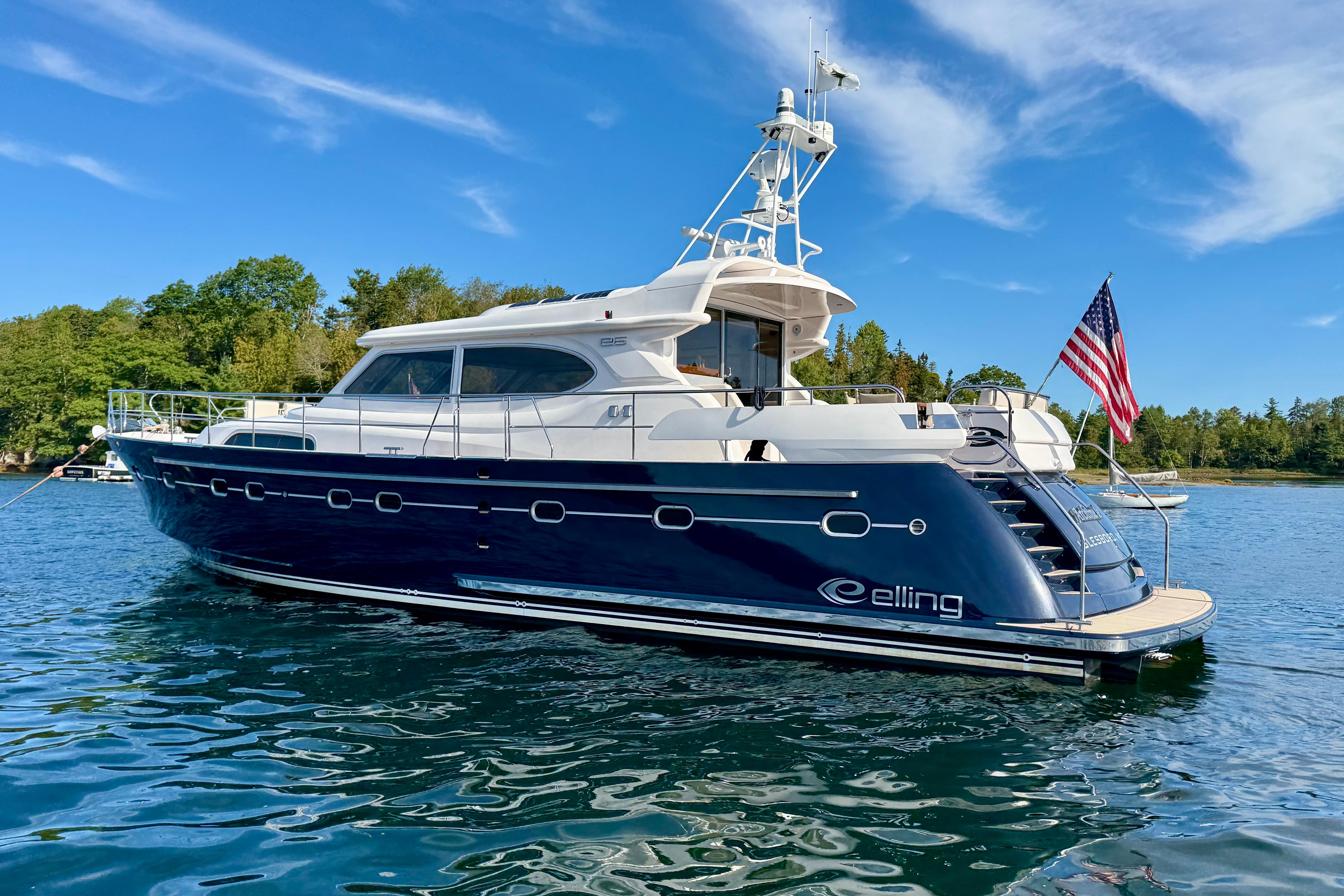 2021 Elling E6 yacht on water, American flag, clear sky, lush greenery.