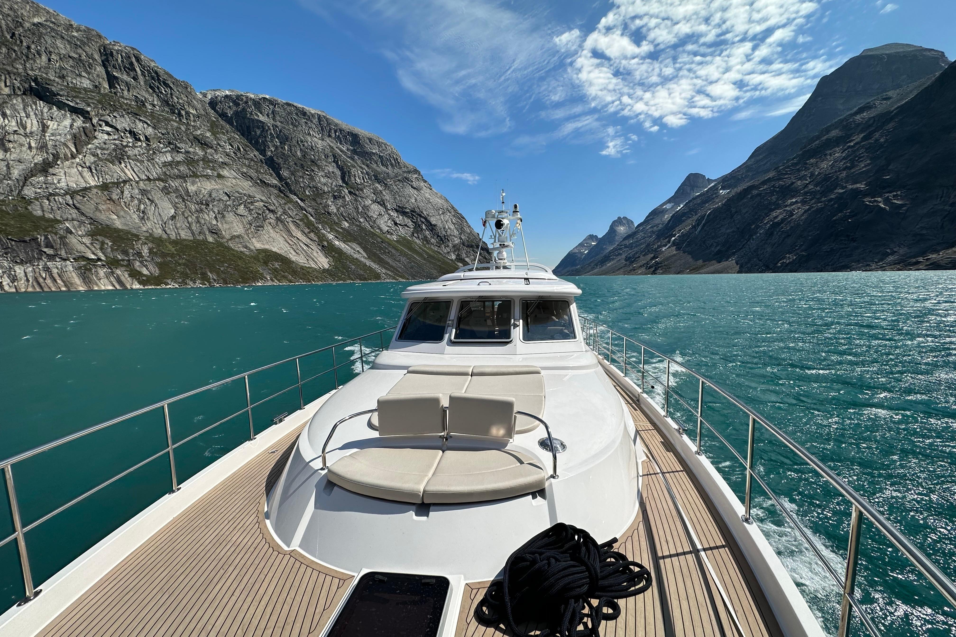 Elling E6 yacht cruising through scenic fjord with turquoise waters and towering cliffs, 2021 model.