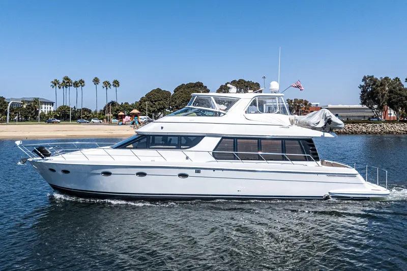  Yacht Photos Pics 2003 Carver 570 Voyager Pilothouse yacht cruising near a scenic shoreline.